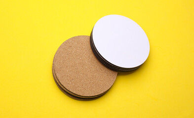 Cork and white coasters for drinks on a yellow background
