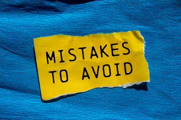Mistakes to avoid message written on ripped torn yellow paper piece with blue background....