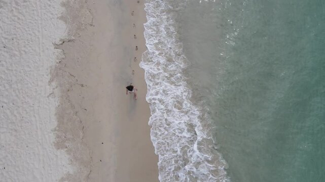 Top view of woman in swimsuit walking alone on the beach.Green sea water, white sand beach, green forest on the shore thailand