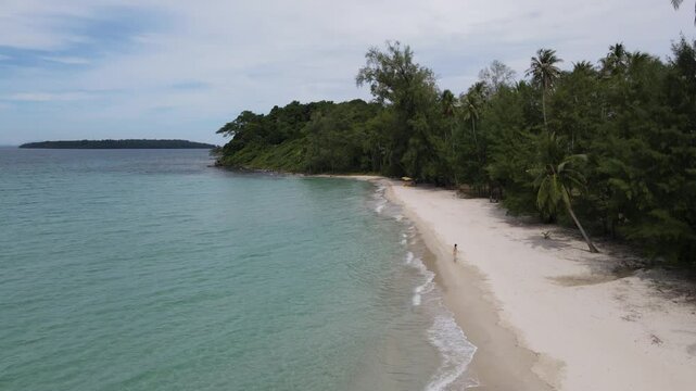 Top view of woman in swimsuit walking alone on the beach.Green sea water, white sand beach, green forest on the shore thailand
