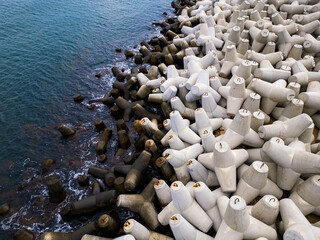 Obraz premium Heavy concrete tetrapods lined along the shoreline at a coastal area during daylight hours