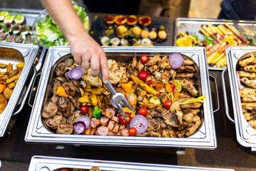 A spread of grilled vegetables, meats, and garnishes at a catering event, showcasing vibrant colors...