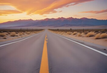 Naklejka premium Empty asphalt road with white lane markings, surrounded by a dramatic sky with orange and yellow sunset colors, and distant mountains in the background