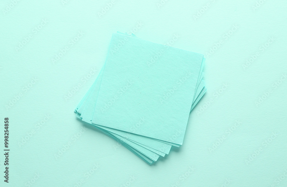 Poster stack of pink square memo sheet of papers on blue background. top view