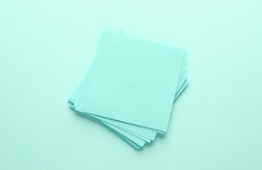 Stack of pink square memo sheet of papers on blue background. Top view