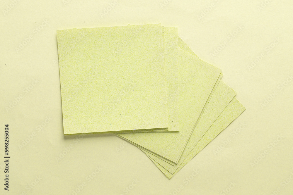 Poster stack of blue square memo sheet of papers on yellow background. top view