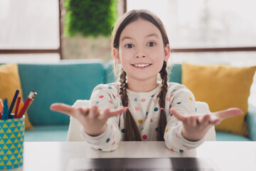 Portrait of charming little girl communicate web camera video call wear pullover modern interior...