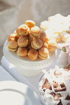 A display of bite-sized savory pastries arranged on a decorative white cake stand, accompanied by other sweet treats in a well-lit reception setting at a wedding