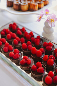 A tray of chocolate desserts garnished with fresh raspberries, perfect for a wedding or special event.