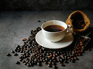 Americano coffee cup and roasted coffee beans falling in a burlap sackon gray background, Black coffee cup aromatic
