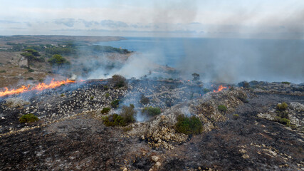 Aerial view of a fire in a countryside near the sea in Puglia, Italy.