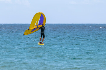 A wing foiler takes advantage of the strong wind blowing on the sea of ​​Santa Margherita di Pula, Sardinia, Italy