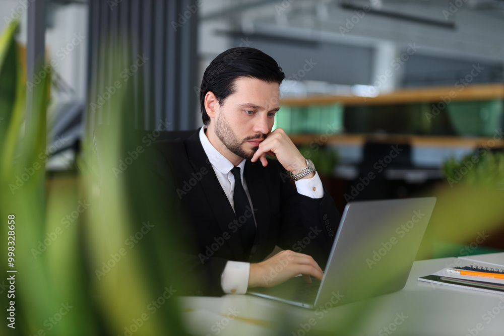 Aufkleber a man in a suit is typing on a laptop computer. he is wearing a watch and has a serious expression o