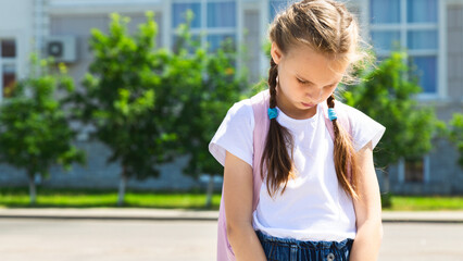 Upset school girl. Back to school. Child girl with backpack has bad emotions because of mark and that children are bullied. Primary school