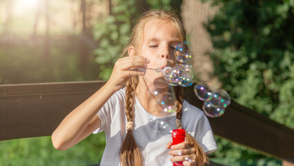 little girl is blowing a soap bubbles