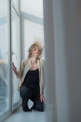 Caucasian woman dancing modern dance on the windowsill. Vertical photo. 