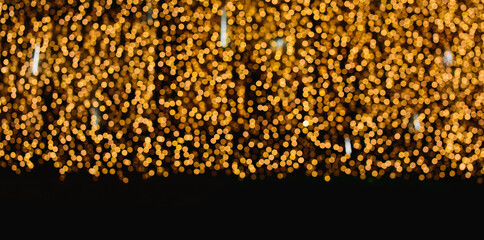 holiday illumination and decoration concept - christmas garland bokeh lights over dark golden...