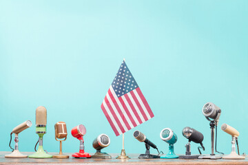 Microphones and USA flag on vintage table front mint blue background. Retro old style filtered photo
