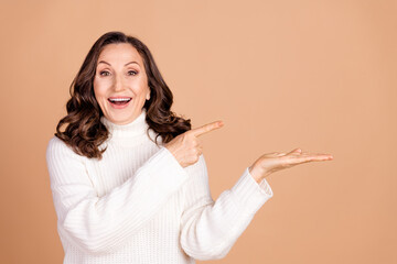 Photo of lovely surprised woman wear white stylish jumper introduce empty space isolated on beige color background