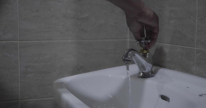 Close up of a man's hand opening the sink faucet.