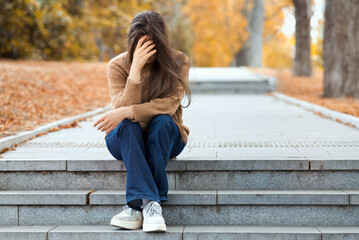 Young woman has mental health problems. Sad and melancholic girl covered her face with her hands...