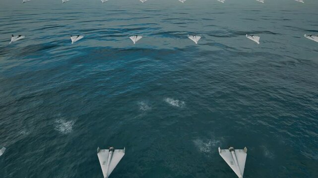 A formation of fixed-wing unmanned combat aerial vehicles (UCAVs), flying at low altitude over the ocean toward their designated targets.
