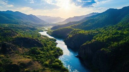 Obraz premium Breathtaking aerial view of a serene river winding through lush green mountains under a vibrant blue sky.
