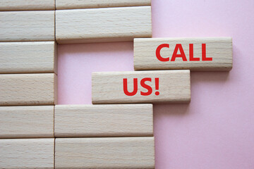 Call Us symbol. Wooden blocks with words Call Us. Beautiful pink background. Business and Call Us...