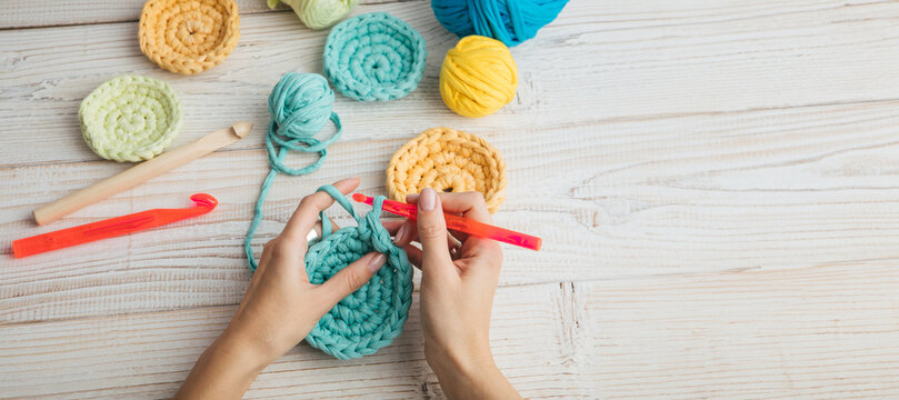 knitting crochet  woman hands top view. colorful balls of yarn blue, yellow and orange. Relaxing hand craft hobby time. Long horizontal banner