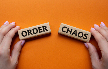 Chaos or Order symbol. Concept word Chaos or Order on wooden blocks. Businessman hand. Beautiful orange background. Business and Chaos or Order concept. Copy space