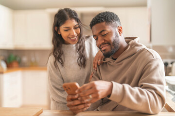 Couple Sharing Joyful Moment While Exploring  Smartphone in Cozy Kitchen During Winter