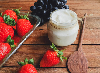 Glass jar with natural yogurt and  wooden background with fruits