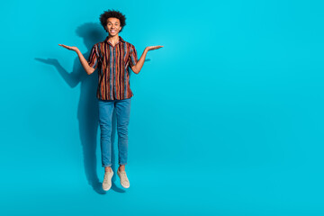 Full size photo of nice young man jump hold empty space vs wear shirt isolated on teal color background