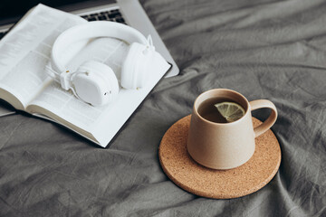 Cup of tea and Holy Bible with laptop on bed in morning devotion time.