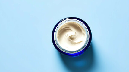 A small jar of cream sits on a blue surface