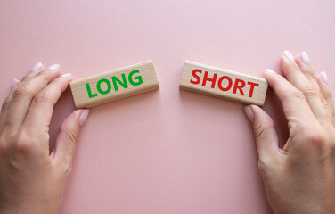 Short vs Long symbol. Concept word Short vs Long on wooden blocks. Businessman hand. Beautiful pink background. Business and Short vs Long concept. Copy space