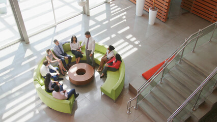 Overhead Shot Of Multi-Cultural Business Team Sitting On Circular Sofa In Modern Office Together © Monkey Business