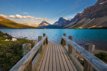 Obraz premium Wooden dock extending towards beautiful blue lake and mountains
