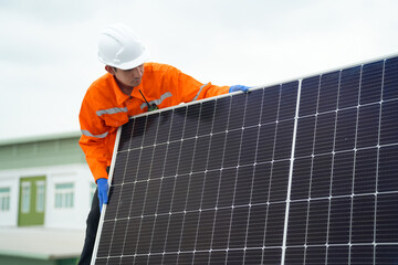 Builder mounting photovoltaic solar modules on roof of house. Back view of man engineer in helmet installing solar panel system outdoors. Concept of alternative and renewable energy.