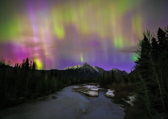 Aurora borealis illuminating a frozen river in the mountains