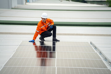 Builder mounting photovoltaic solar modules on roof of house. Back view of man engineer in helmet installing solar panel system outdoors. Concept of alternative and renewable energy.