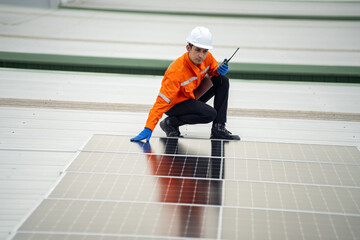 Builder mounting photovoltaic solar modules on roof of house. Back view of man engineer in helmet installing solar panel system outdoors. Concept of alternative and renewable energy.
