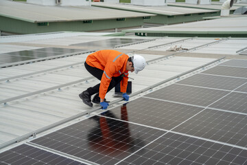 Builder mounting photovoltaic solar modules on roof of house. Back view of man engineer in helmet installing solar panel system outdoors. Concept of alternative and renewable energy.