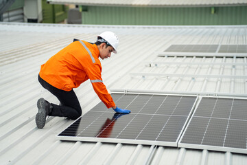 Builder mounting photovoltaic solar modules on roof of house. Back view of man engineer in helmet installing solar panel system outdoors. Concept of alternative and renewable energy.