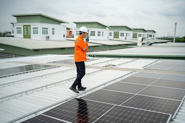 Builder mounting photovoltaic solar modules on roof of house. Back view of man engineer in helmet installing solar panel system outdoors. Concept of alternative and renewable energy.