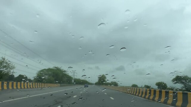 Heavy raining during monsoon and droplets textured on glass of moving car in the highway roads.