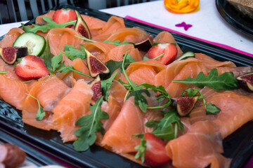 Closeup of sliced salmon in a black plate at the party buffet