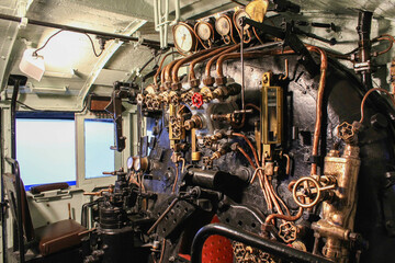 Vintage steam locomotive interior cockpit with brass gauges and pipes