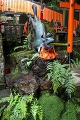 Bronze fox fountain pouring water into stone basin at Kyoto shrine