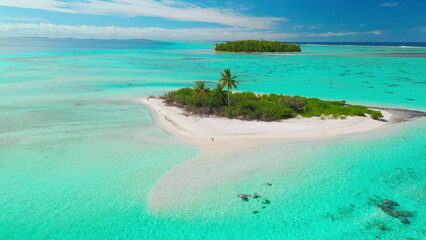 Turquoise waters surround a small island with palm trees on white sand beaches under a clear blue sky, inviting you to escape to this breathtaking tropical paradise captured by a drone